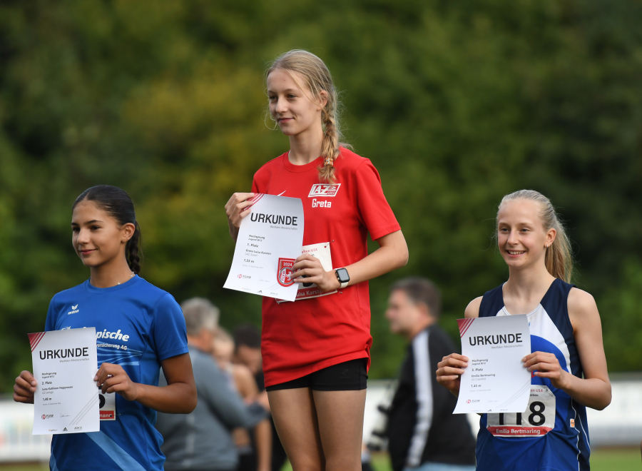 W12-Hochsprung-Siegerehrung in Kamen: In der Mitte Westfalenmeisterin Greta Karsten vom LAZ Soest. Links Vizemeisterin Lena Kathleen Hoppmann (LG Lemgo), rechts die Dritte , Emilia Bertmaring (LG Coesfeld). Foto: Bottin